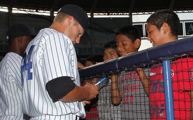 A baseball player signing autographs for some kids