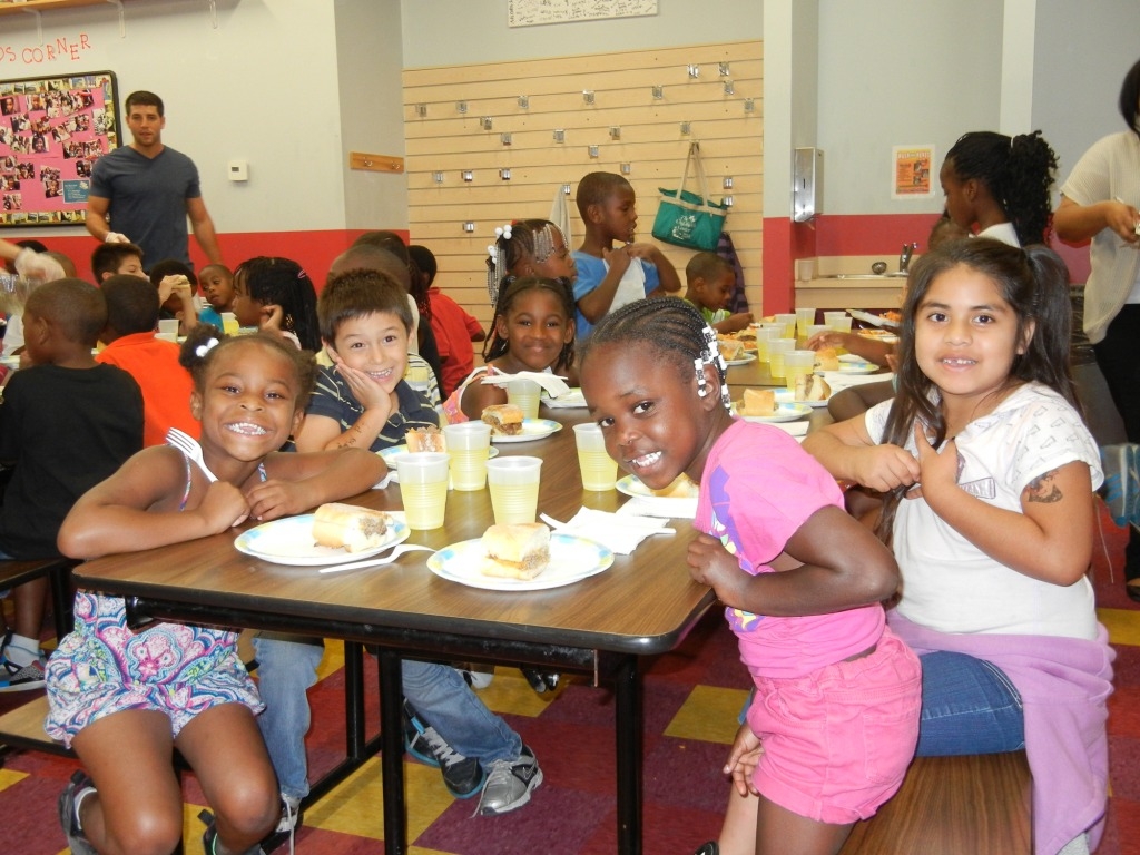 A group of children sitting at a table eating food.