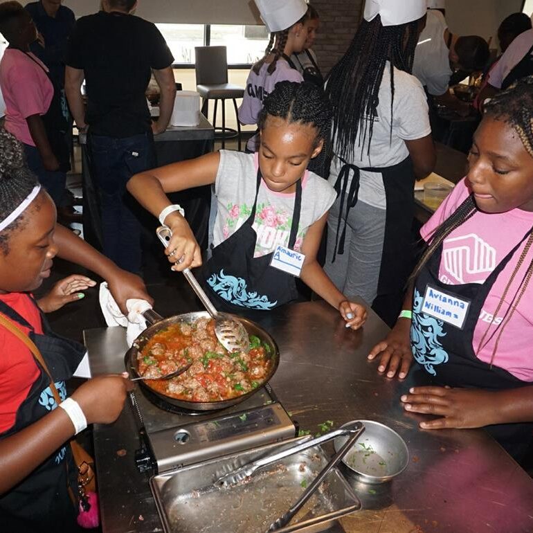 A group of people cooking food in a kitchen.