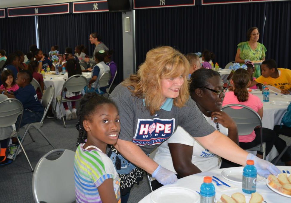 A woman and girl sitting at tables with people.